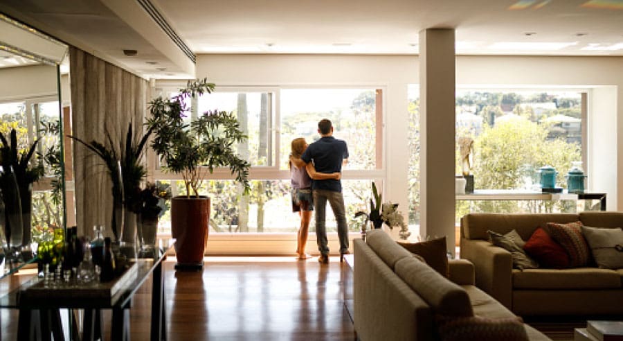 People standing in a living room with a lot of natural lighting.
